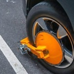 yellow wheel clamp locked with messing lock on an illegally park950x575