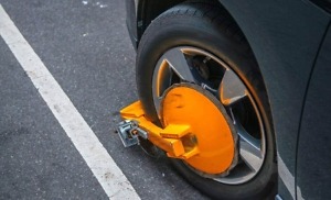 yellow wheel clamp locked with messing lock on an illegally park950x575